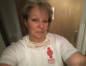 Eine freundliche Mitarbeiterin vom Pflegedienst Kremer in Arbeitskleidung steht für eine hochwertige Pflege und ambulante Betreuung in Deutschland.
