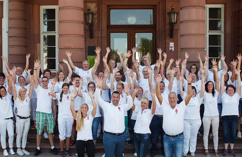 Mitarbeiter Gruppenfoto. Alle haben die Arme oben und lachen.