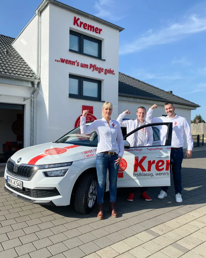 3 Kremer Mitarbeiter vor dem Kremerauto mit Arm nach oben