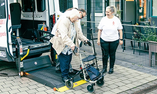 Standort_Gruendau_1 2 Mitarbeiter an Laderampe des Wagens mit Klientin