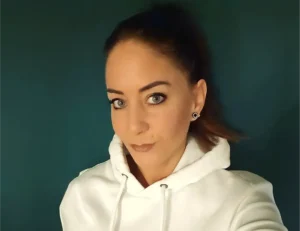 Eine freundliche Mitarbeiterin vom Pflegedienst Kremer für hochwertige Pflege und ambulante Betreuung vor einem schlichten, dunklen Hintergrund.