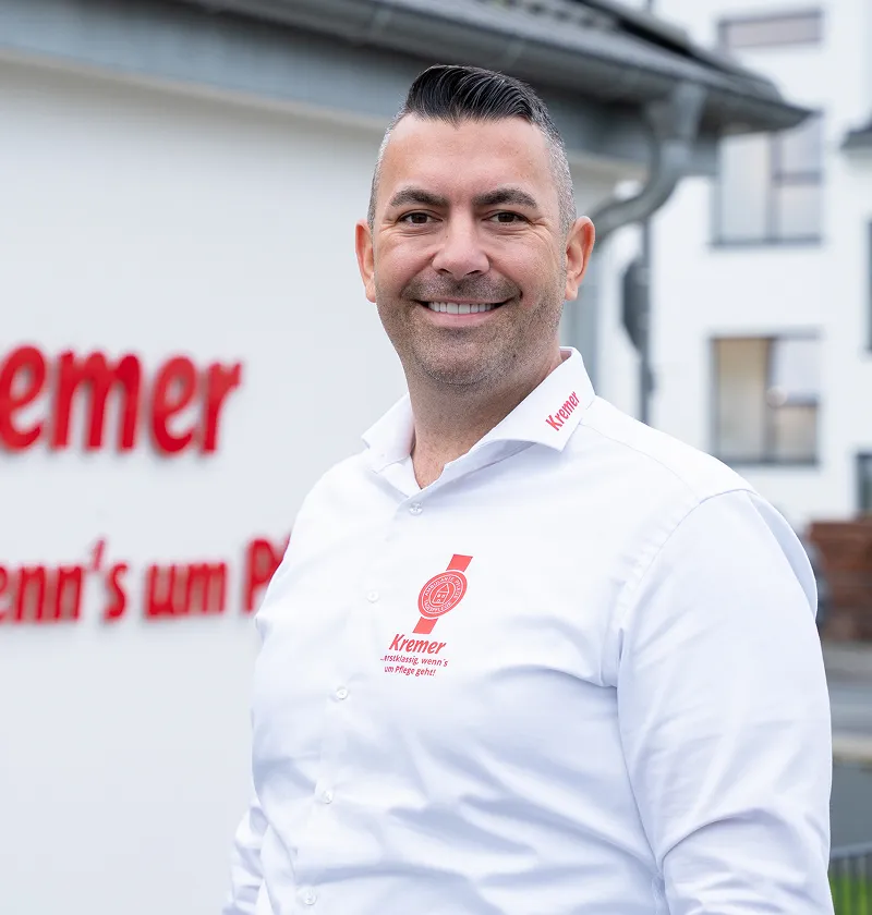 Ein freundlicher Mitarbeiter vom Pflegedienst Kremer im Main-Kinzig-Kreis steht vor dem Firmengebäude für eine professionelle Pflegeberatung bereit.