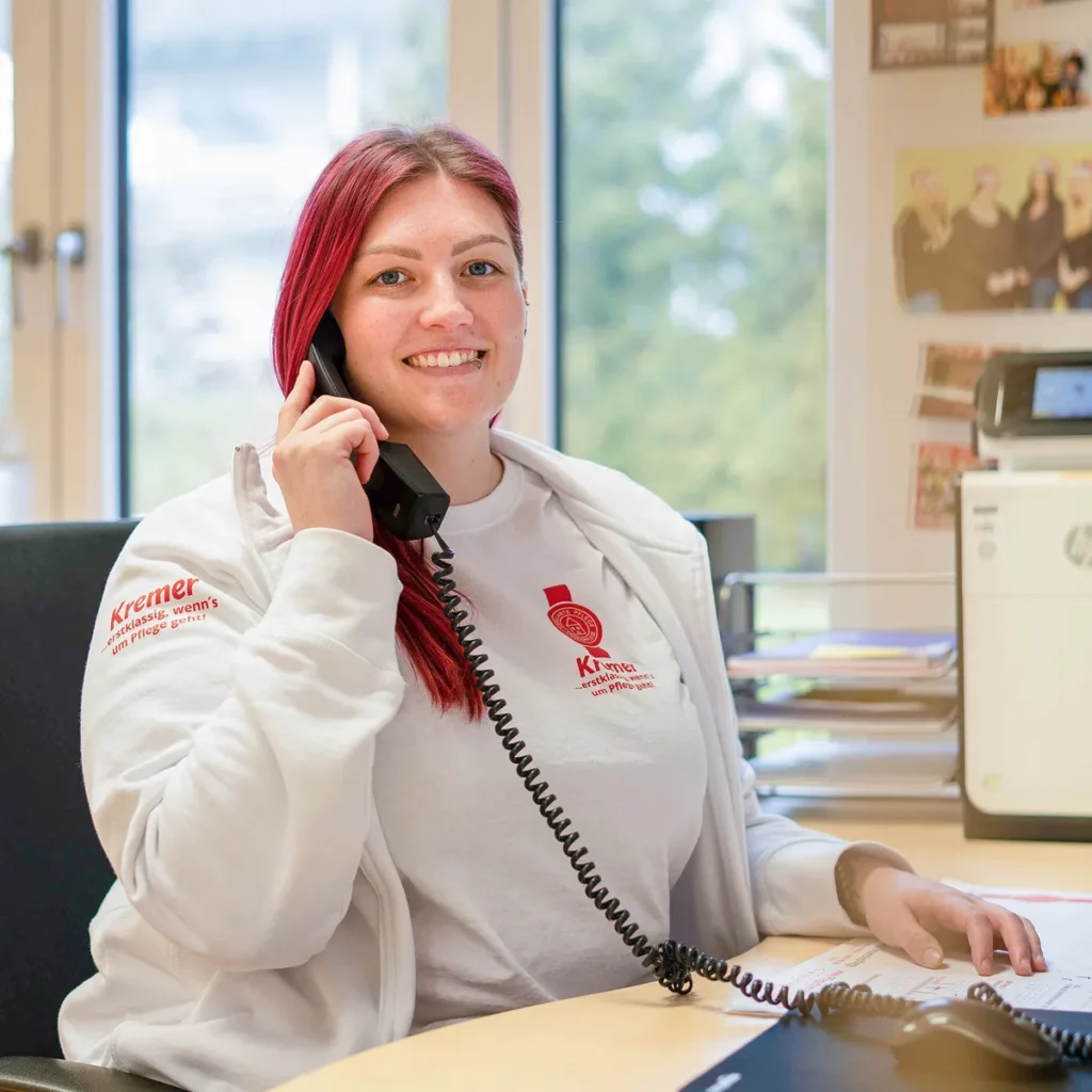 Eine freundliche Mitarbeiterin vom Pflegedienst Kremer führt ein Telefonat für die professionelle Pflegeberatung im Main-Kinzig-Kreis.