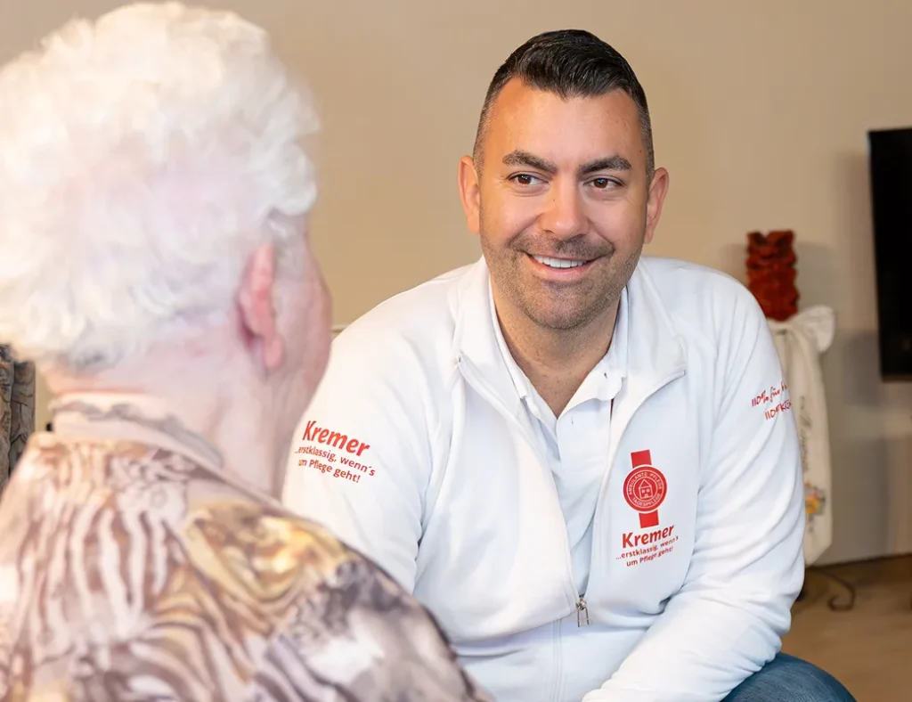 Ein freundlicher Mitarbeiter vom Pflegedienst Kremer führt ein persönliches Gespräch im Rahmen der Pflegeberatung mit einer älteren Dame zu Hause.
