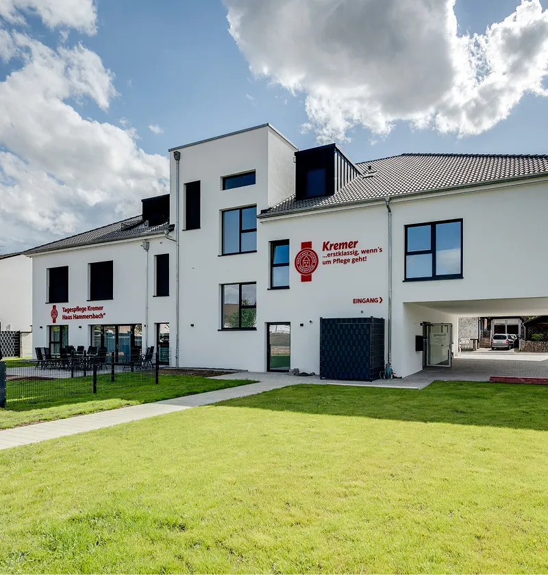 Das moderne Gebäude vom Pflegedienst Kremer für die Tagespflege MKK mit gepflegter Außenanlage und einladendem Eingangsbereich bei sonnigem Wetter.